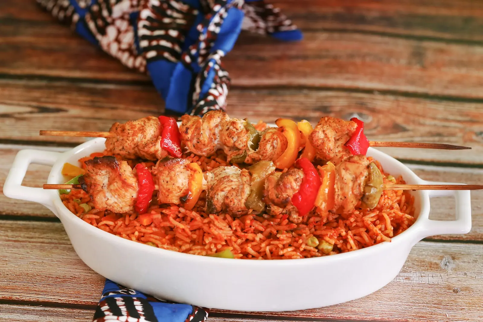 Smoky jollof rice topped with grilled chicken skewers